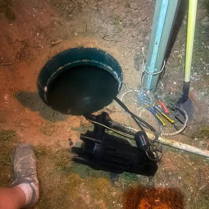 An open pump basin with the pump, floats and wiring laid out beside it during installation